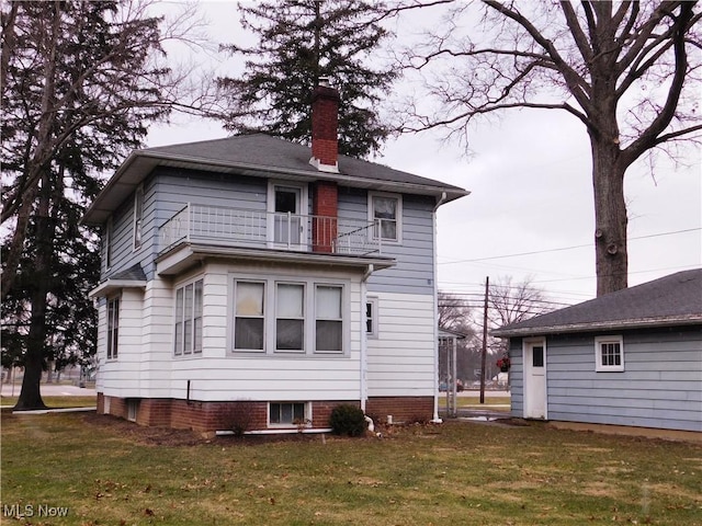 rear view of property featuring a lawn and a balcony