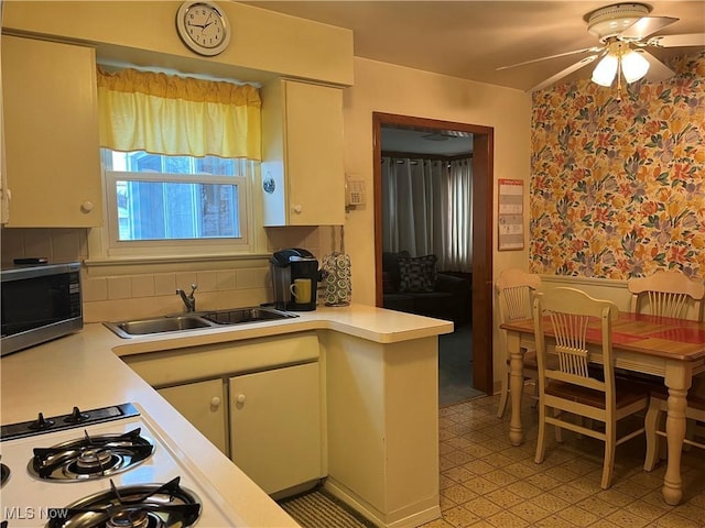 kitchen featuring sink, gas cooktop, ceiling fan, backsplash, and kitchen peninsula