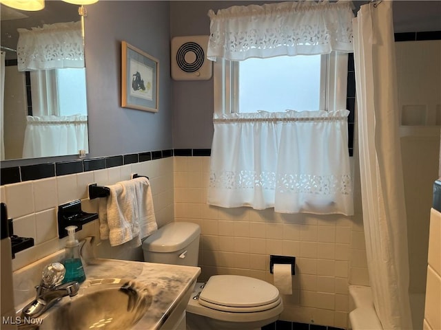 bathroom featuring vanity, toilet, and tile walls