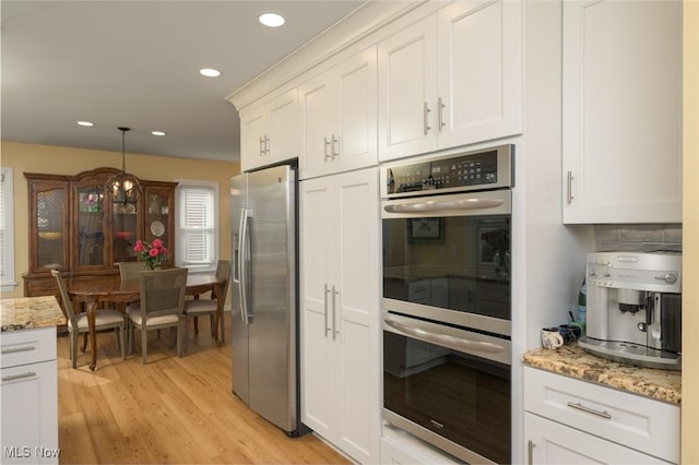 kitchen with appliances with stainless steel finishes, light hardwood / wood-style flooring, and white cabinets