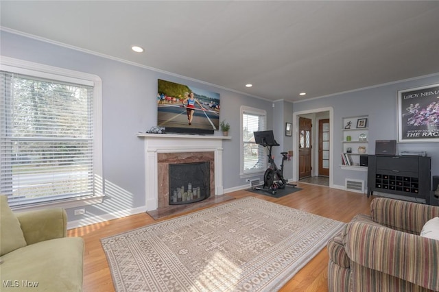 living room featuring ornamental molding, wood-type flooring, and a high end fireplace