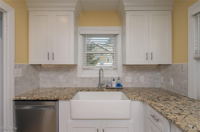 kitchen featuring light stone counters, sink, stainless steel dishwasher, and white cabinets