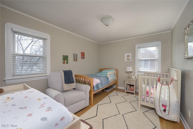 bedroom featuring multiple windows, ornamental molding, and light wood-type flooring