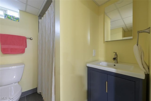 bathroom featuring vanity, tile patterned flooring, a paneled ceiling, and toilet