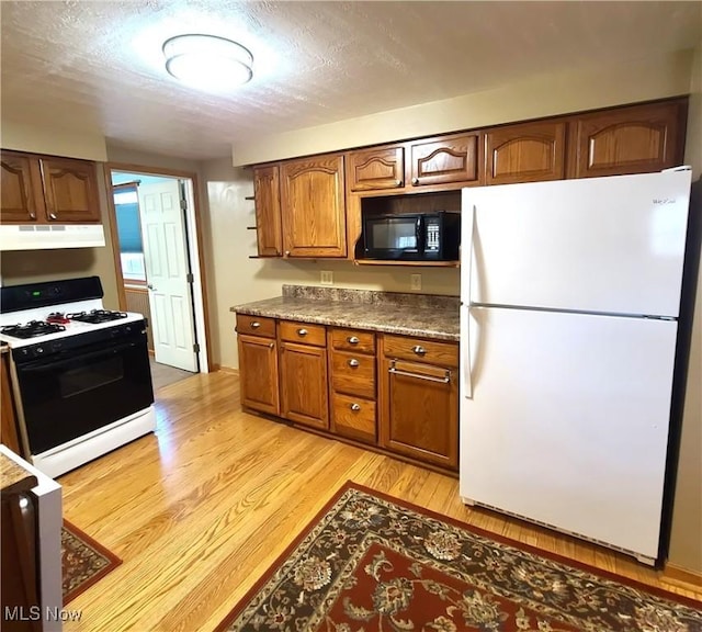 kitchen featuring gas stove, white fridge, a textured ceiling, and light hardwood / wood-style floors