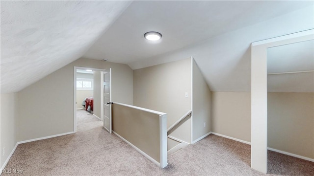 bonus room with vaulted ceiling and light colored carpet