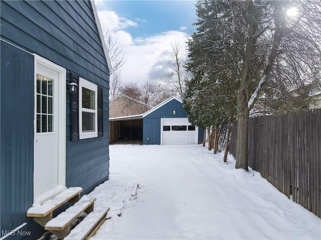 yard covered in snow featuring a garage and an outdoor structure