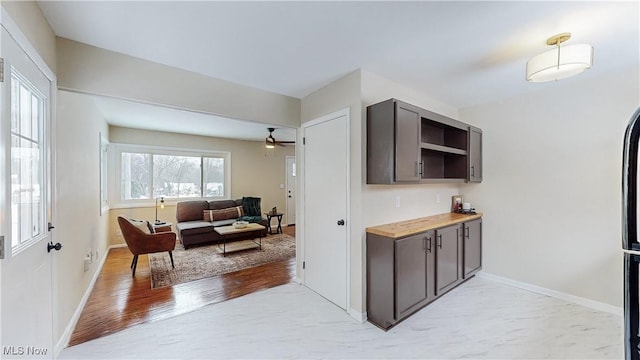 kitchen with wood counters, dark brown cabinetry, ceiling fan, and light wood-type flooring