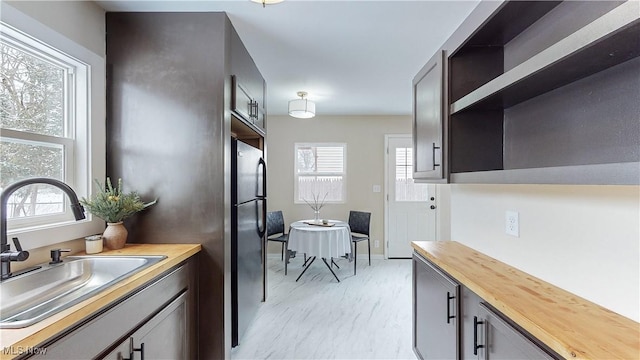 kitchen with butcher block counters, sink, and stainless steel refrigerator