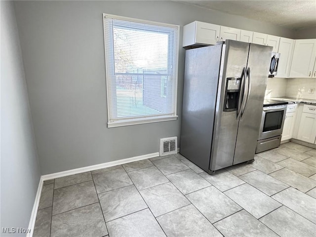 kitchen featuring white cabinetry, light tile patterned floors, decorative backsplash, and appliances with stainless steel finishes