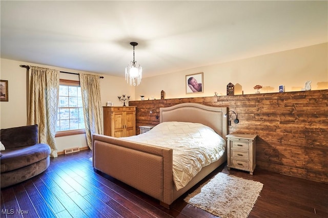 bedroom featuring an inviting chandelier and dark wood-type flooring