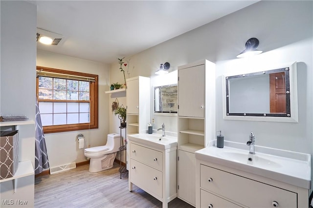 bathroom with toilet, vanity, and wood-type flooring