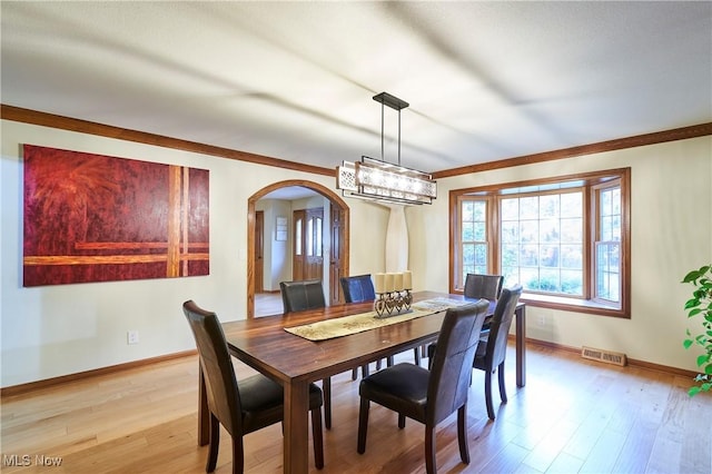 dining space with crown molding and light hardwood / wood-style flooring