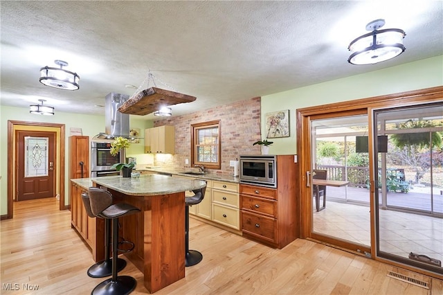 kitchen featuring light wood-type flooring, a center island, light stone countertops, sink, and appliances with stainless steel finishes