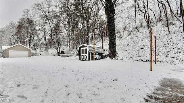 yard covered in snow featuring a storage unit and a garage