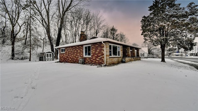 view of snow covered exterior featuring a storage shed