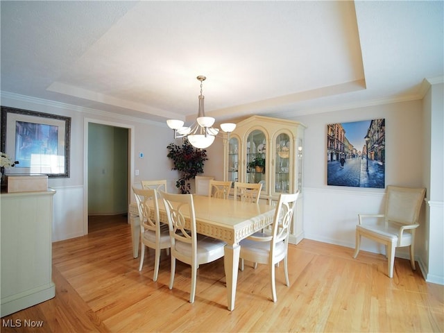 dining room featuring a raised ceiling, light hardwood / wood-style floors, and a notable chandelier