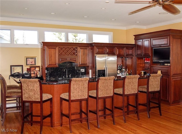 kitchen with hardwood / wood-style flooring, a breakfast bar area, and stainless steel fridge