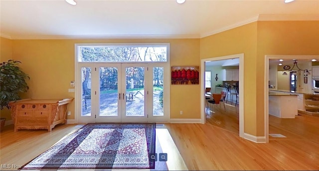 doorway to outside with light wood-type flooring, ornamental molding, and a healthy amount of sunlight