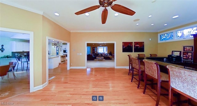 interior space with ceiling fan, light hardwood / wood-style flooring, crown molding, and indoor bar