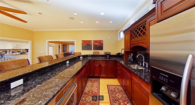 kitchen featuring a breakfast bar, sink, stainless steel refrigerator with ice dispenser, dark stone counters, and kitchen peninsula