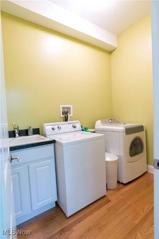 washroom with cabinets, light wood-type flooring, sink, and washer and clothes dryer