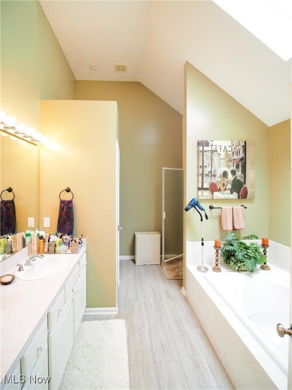 bathroom featuring hardwood / wood-style floors, a tub, lofted ceiling, and vanity