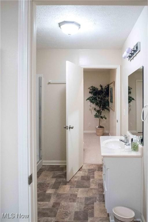 bathroom with vanity, a shower with door, and a textured ceiling