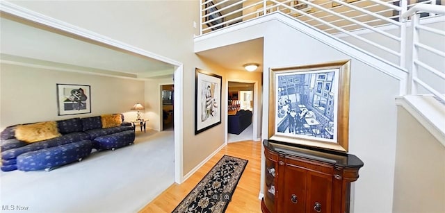 hall featuring a high ceiling and light hardwood / wood-style floors