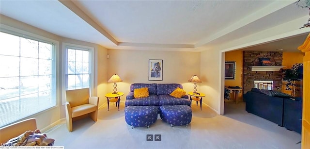 living area featuring a fireplace, a raised ceiling, and carpet