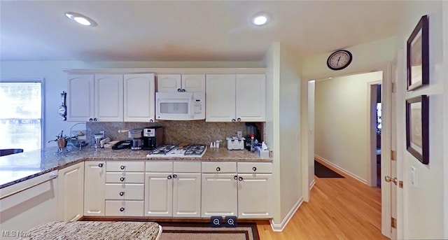 kitchen with light stone countertops, light hardwood / wood-style floors, backsplash, white appliances, and white cabinets