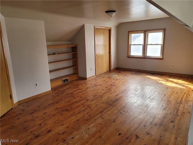 additional living space featuring vaulted ceiling and wood-type flooring