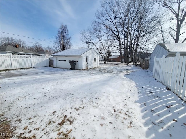 snowy yard featuring a garage and an outdoor structure