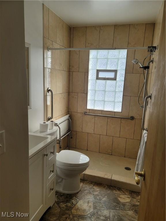 bathroom with toilet, vanity, and tiled shower