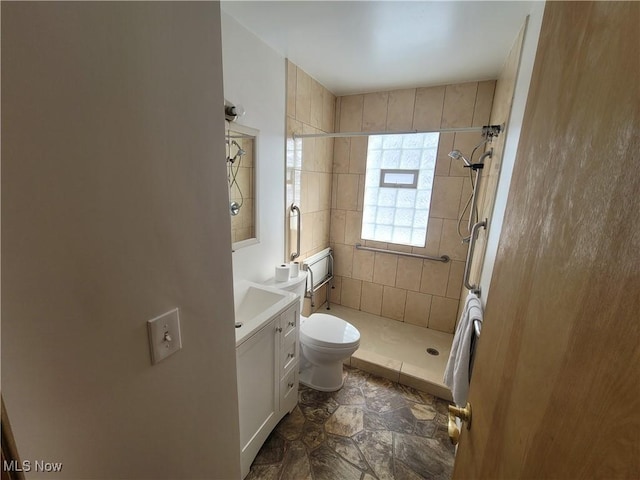 bathroom with vanity, tiled shower, and toilet