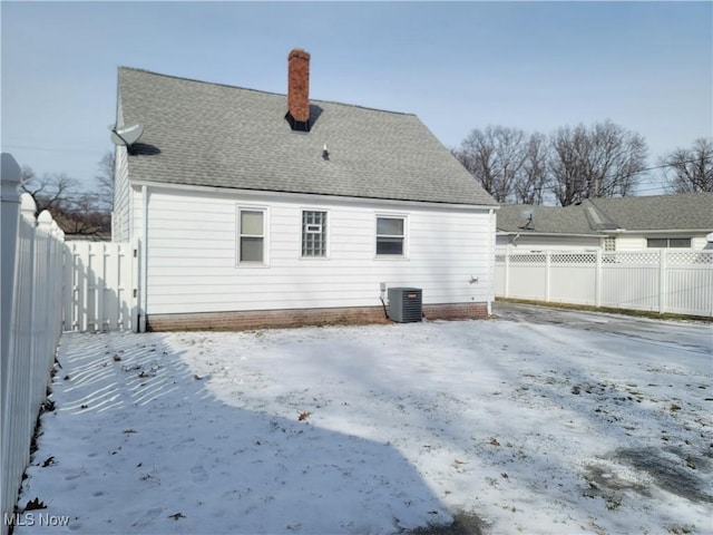 snow covered rear of property featuring cooling unit