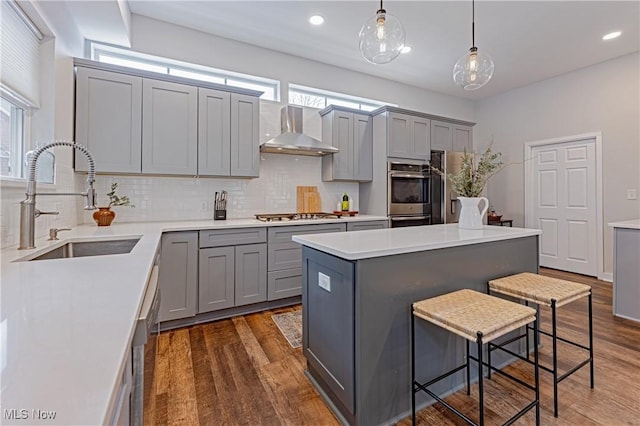 kitchen featuring plenty of natural light, pendant lighting, sink, and wall chimney exhaust hood