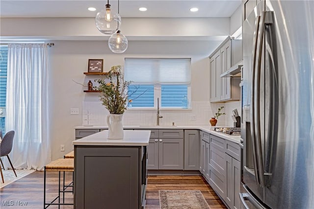 kitchen featuring a kitchen island, sink, gray cabinets, appliances with stainless steel finishes, and pendant lighting