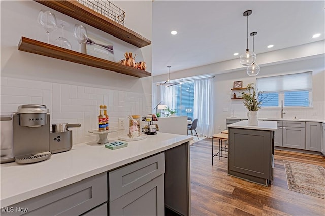 kitchen with a center island, pendant lighting, gray cabinetry, dark hardwood / wood-style floors, and decorative backsplash