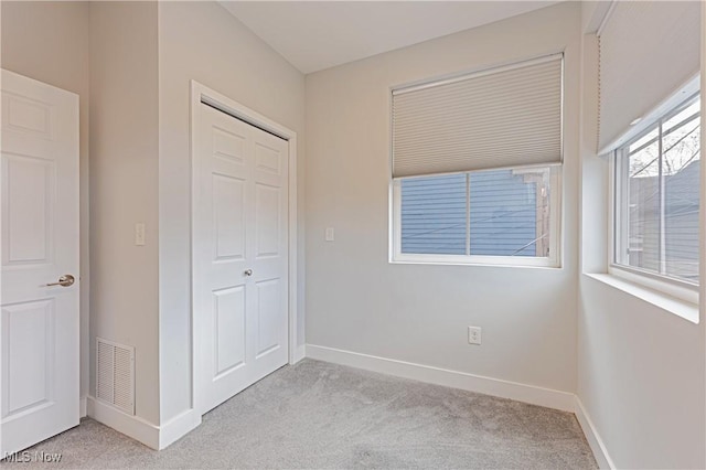 unfurnished bedroom featuring a closet and light colored carpet