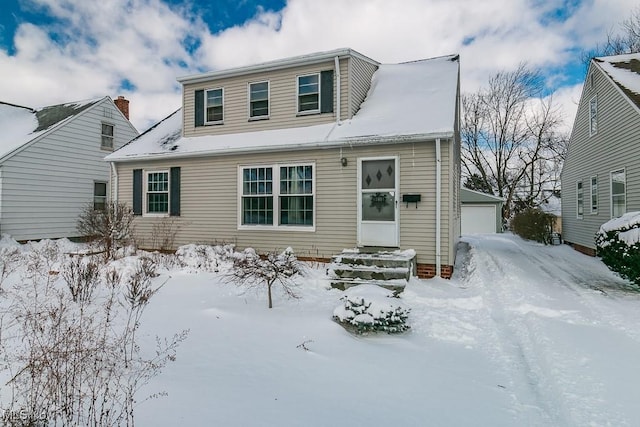 snow covered back of property with a garage and an outdoor structure