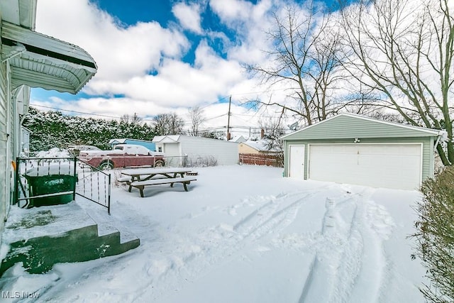 yard covered in snow with an outbuilding and a garage