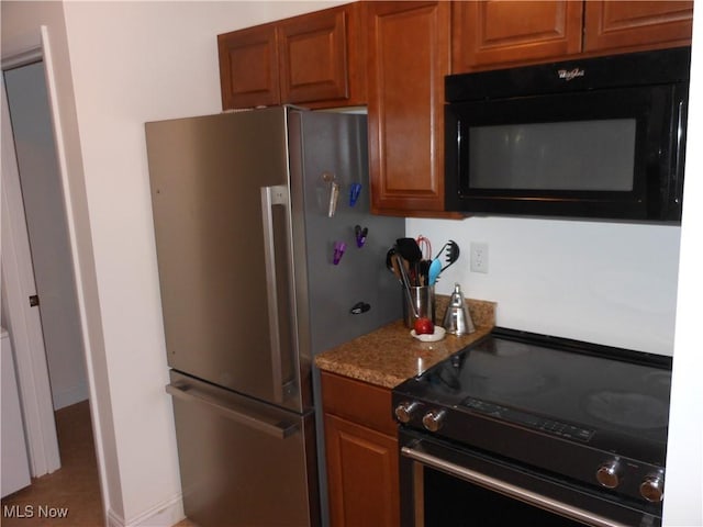 kitchen featuring light stone countertops and black appliances