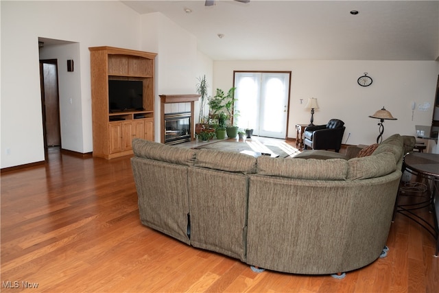 living room with vaulted ceiling, wood-type flooring, and a tiled fireplace