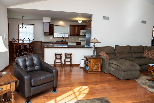 living room with light hardwood / wood-style flooring, sink, and a notable chandelier