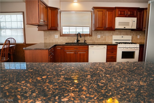 kitchen featuring white appliances, dark stone countertops, sink, and tasteful backsplash