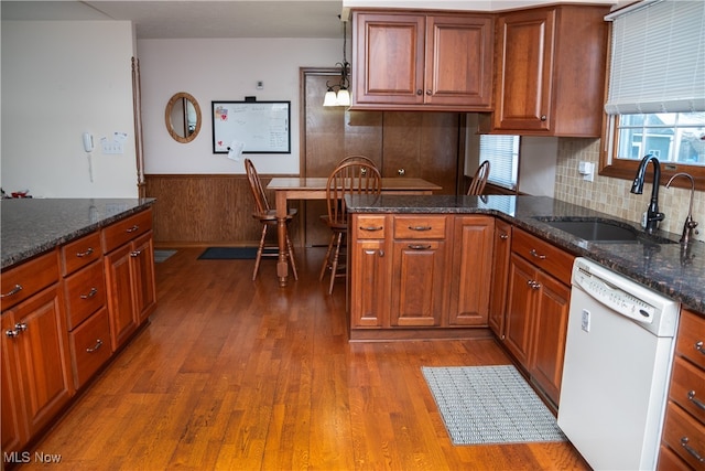 kitchen with dark hardwood / wood-style flooring, sink, dishwasher, and dark stone counters