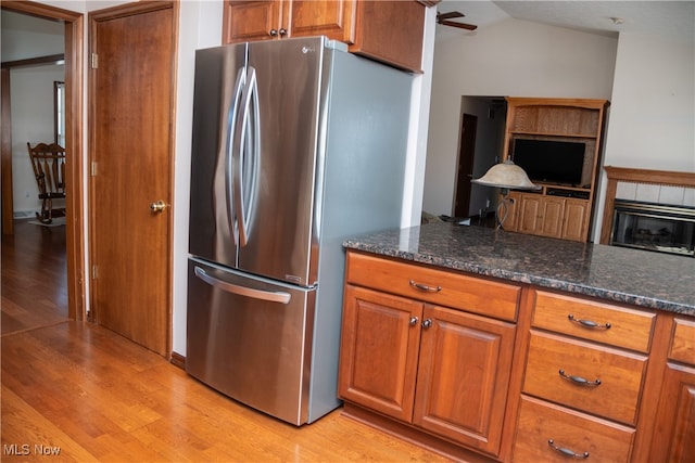 kitchen featuring light hardwood / wood-style floors, dark stone counters, stainless steel fridge, and lofted ceiling