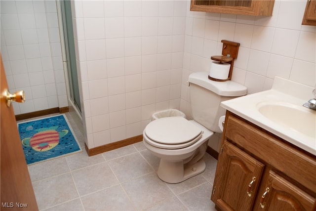 bathroom with tile walls, vanity, an enclosed shower, toilet, and tile patterned floors