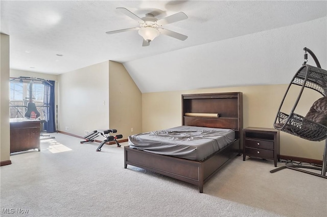 bedroom featuring ceiling fan, vaulted ceiling, light carpet, and a textured ceiling